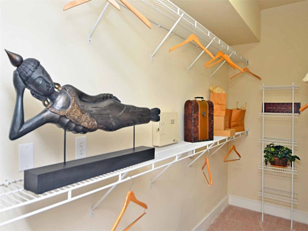a closet with a statue of a person on the wall and a shelf with luggage