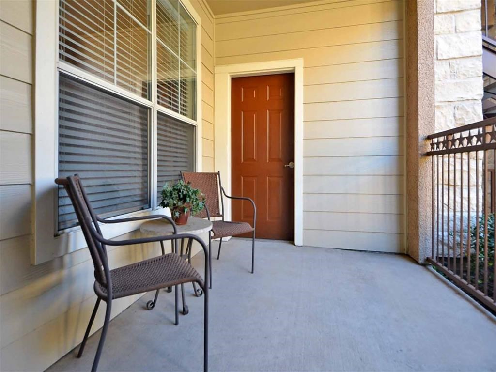 the front porch of a house with two chairs and a table