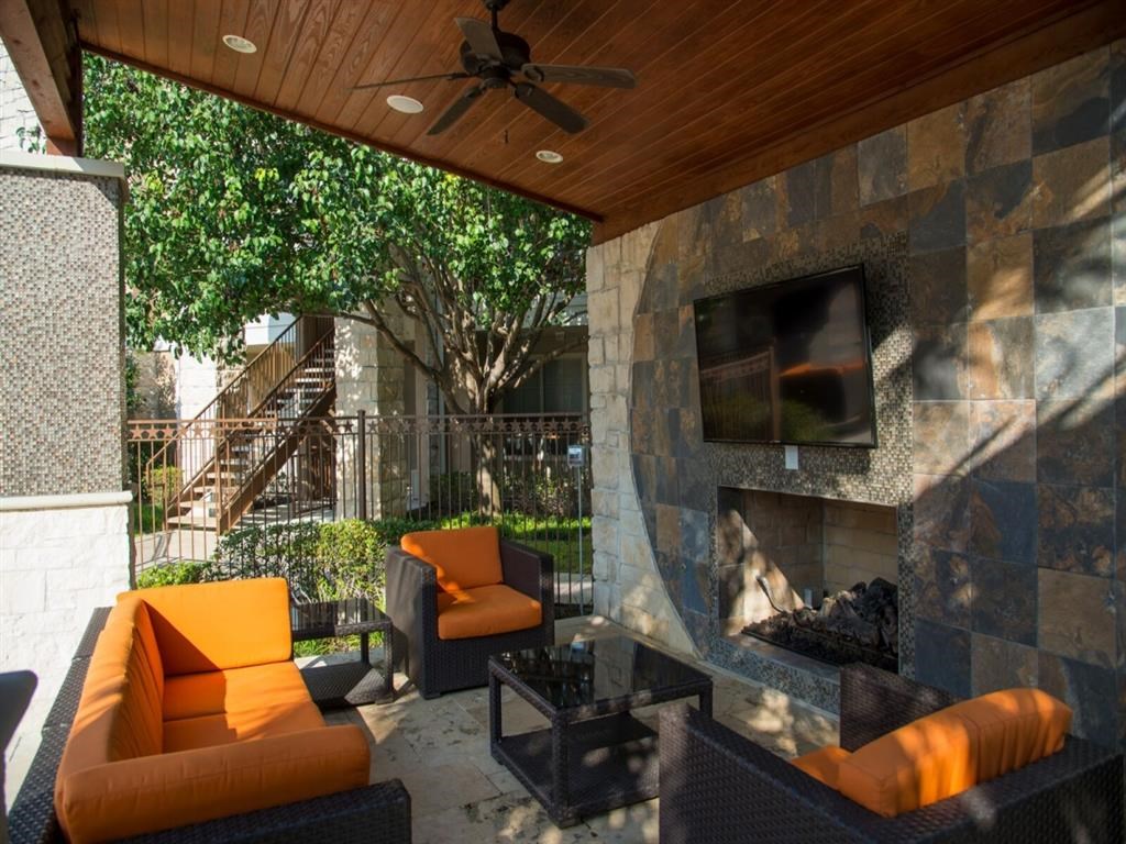 outdoor living room with a stone fireplace and orange furniture