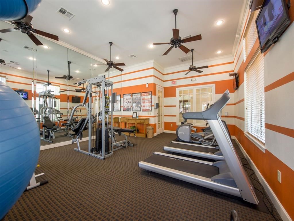 a gym with a lot of machines and ceiling fans