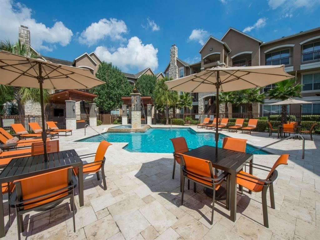 a large swimming pool with orange chairs and umbrellas