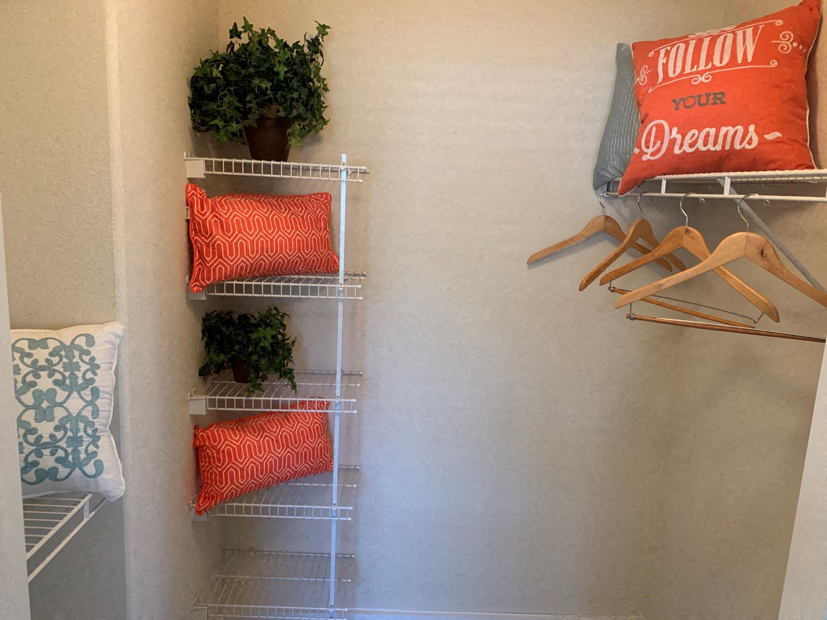 a closet with pillows and plants and hooks on the wall