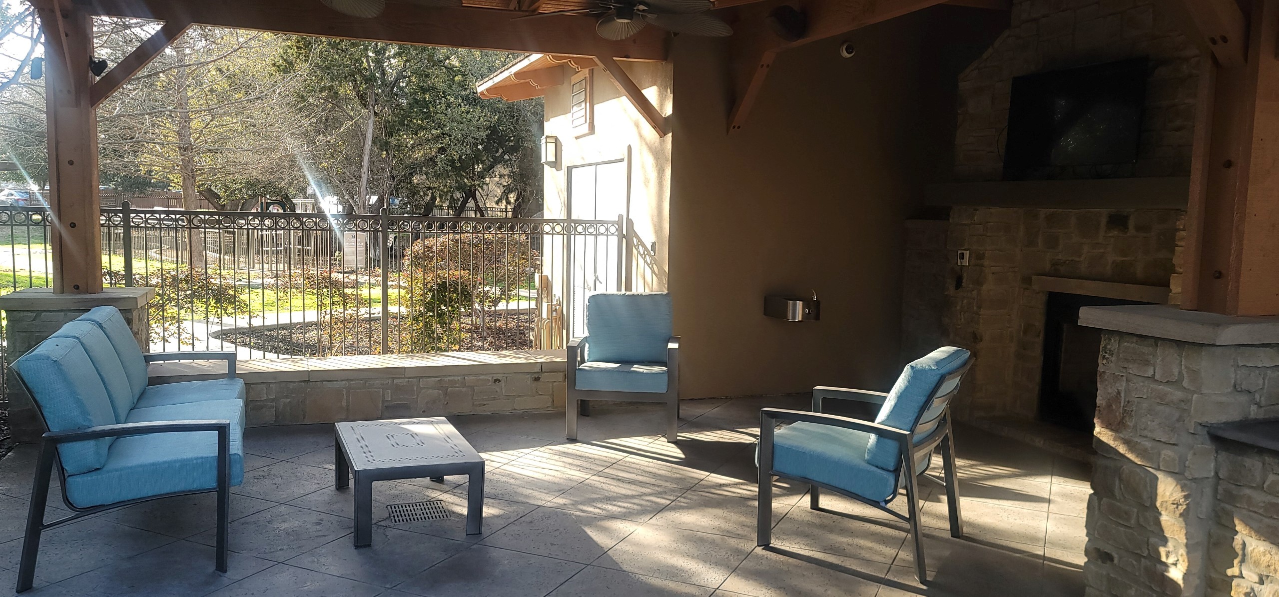 a patio with blue chairs and a fireplace