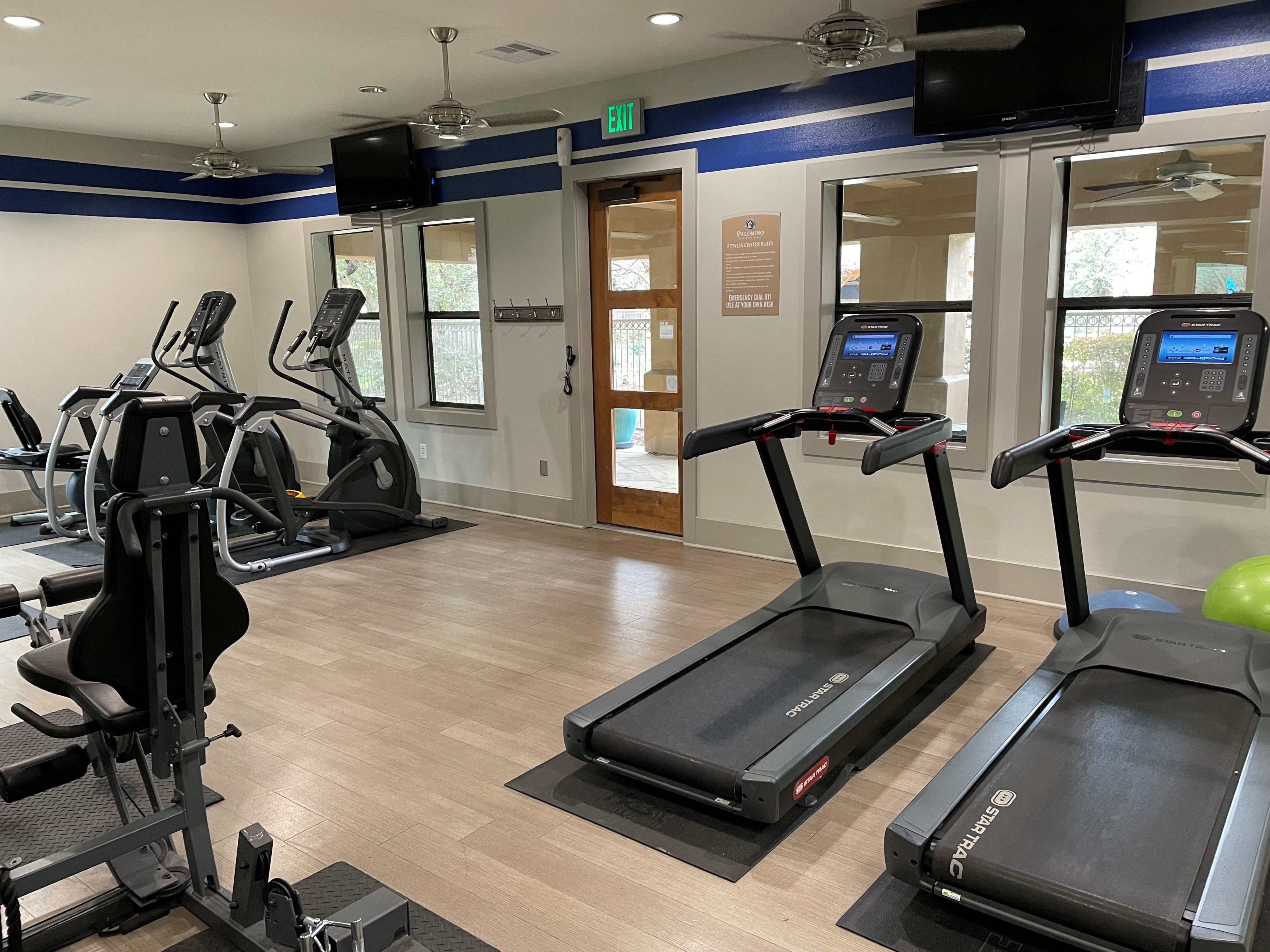 a gym with cardio equipment and a tv