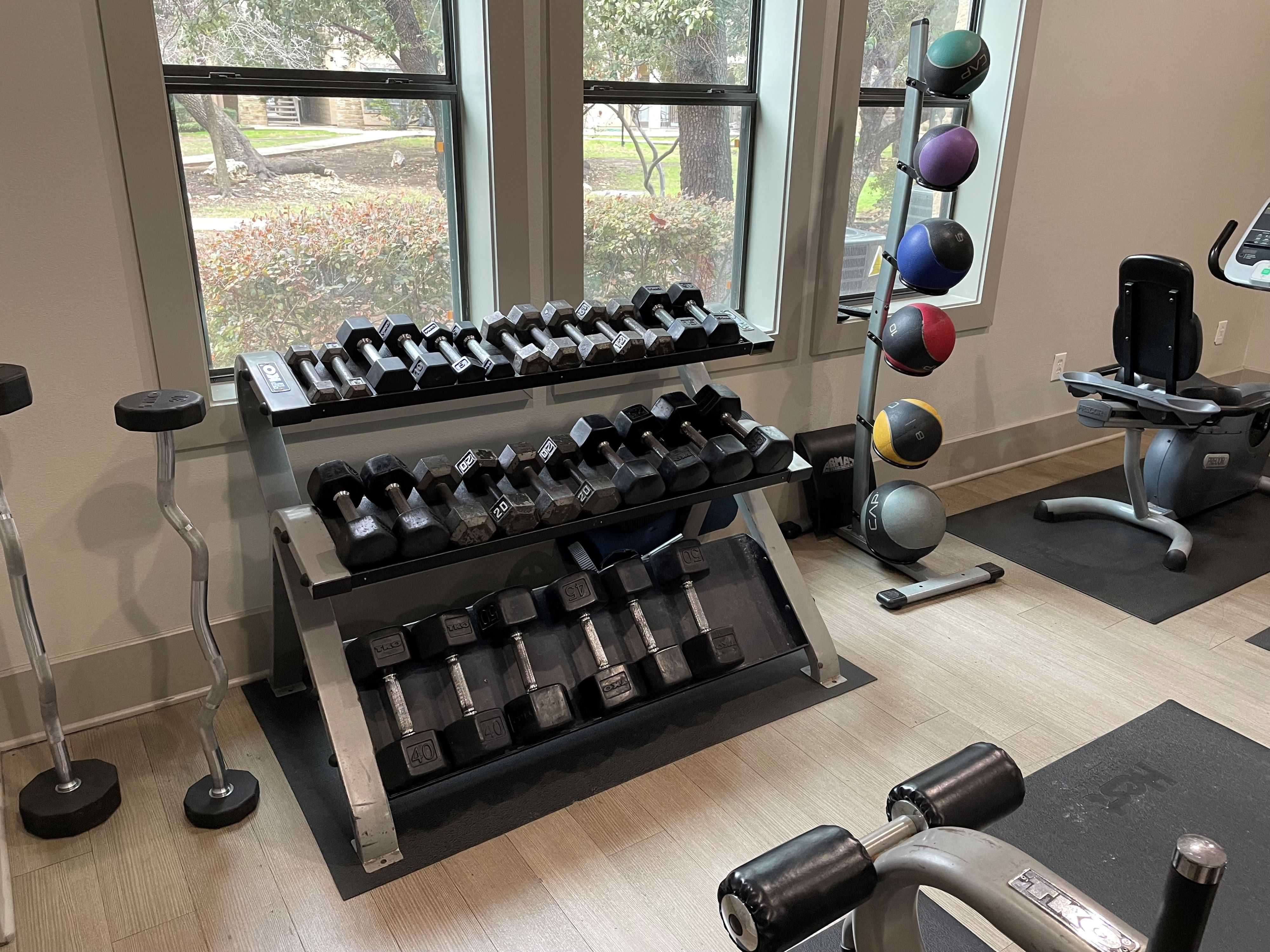 a fitness room with weights and a rack of dumbbells