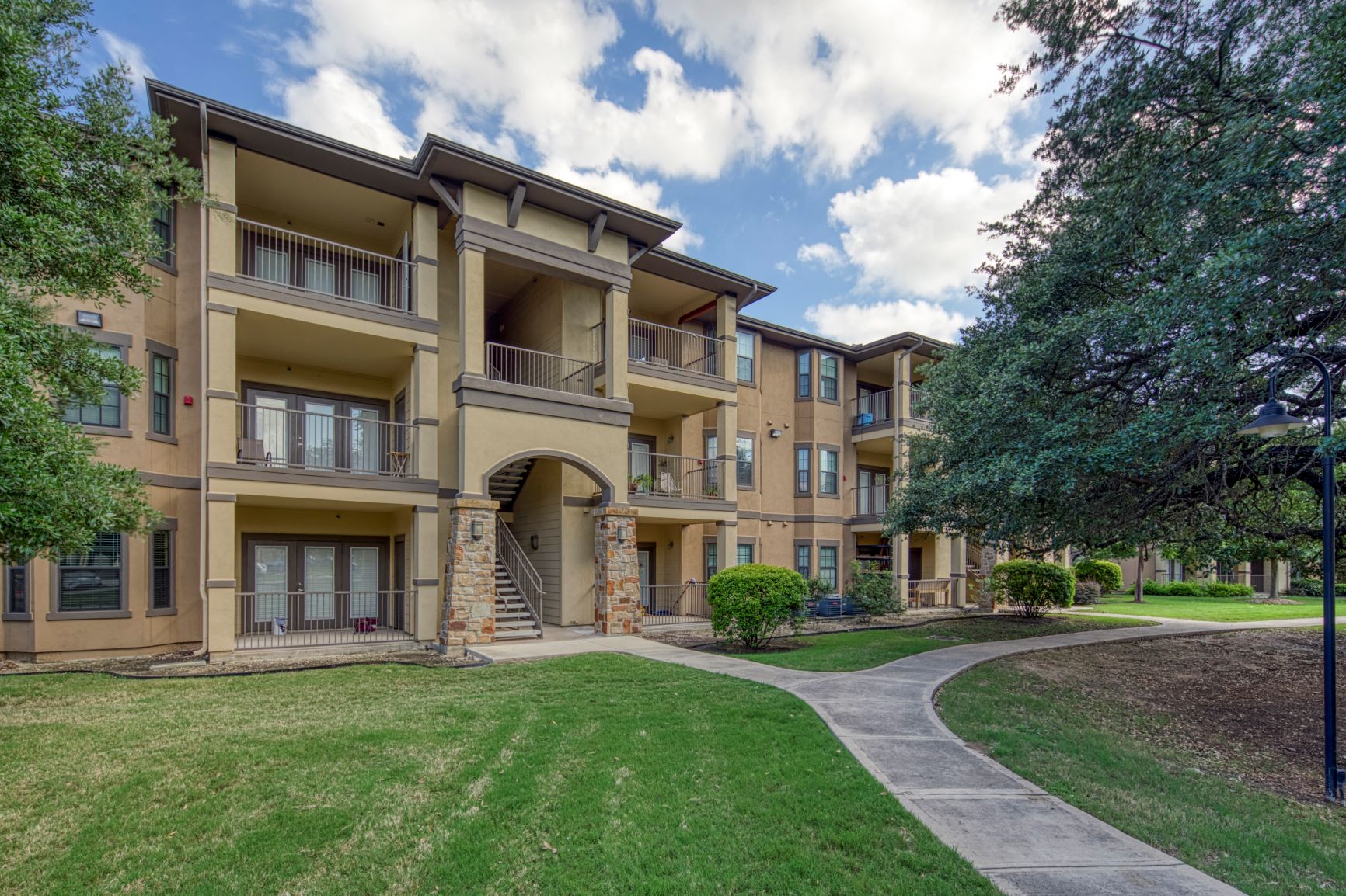 an exterior view of an apartment building with grass and trees