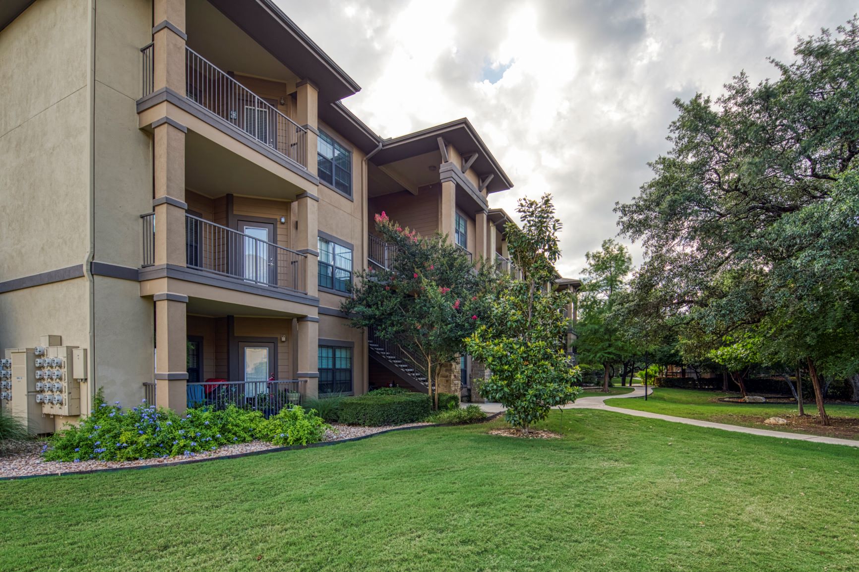 an apartment building with a green lawn and trees