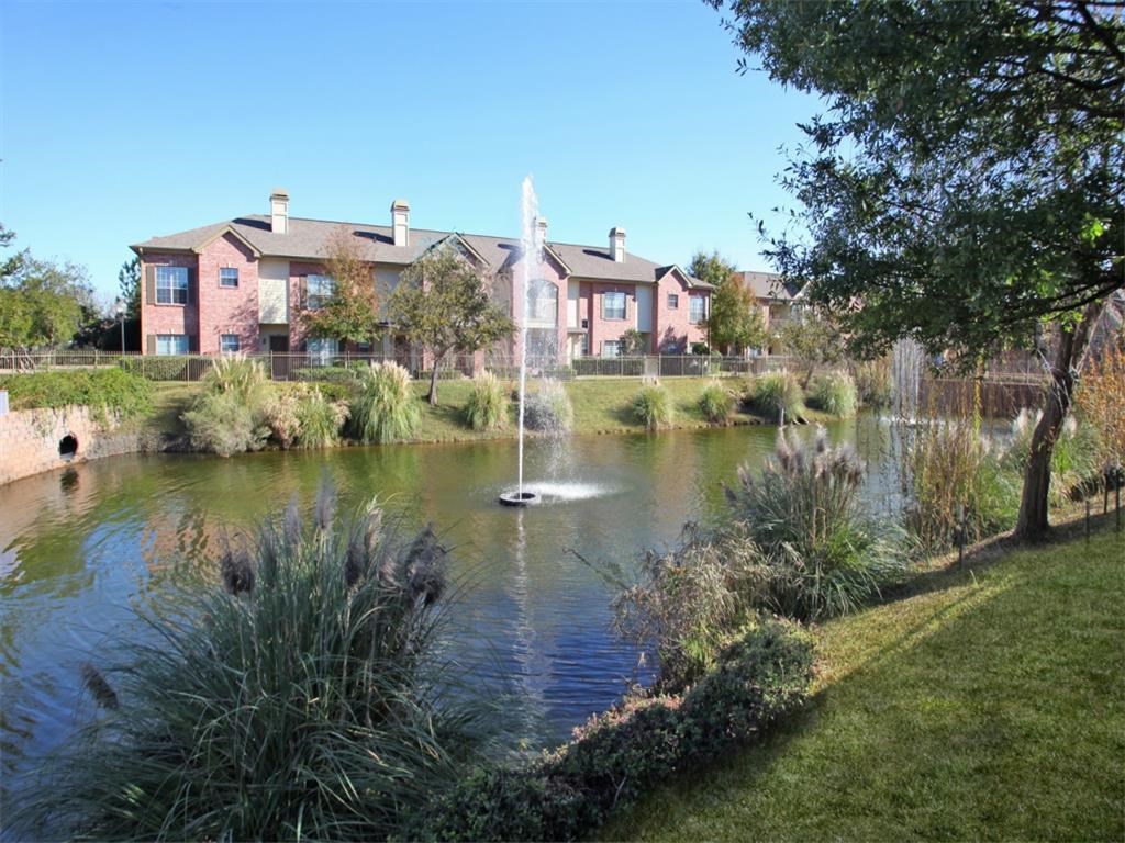 a fountain in the middle of a pond in front of a building