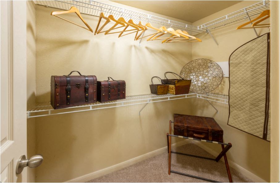 a closet with suitcases on shelves and a table