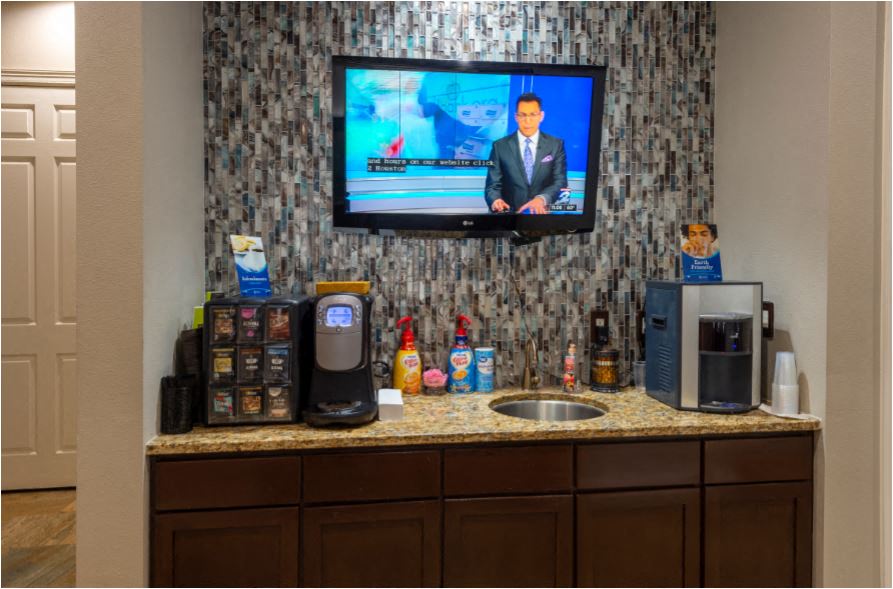 a kitchen with a sink and a tv on the wall