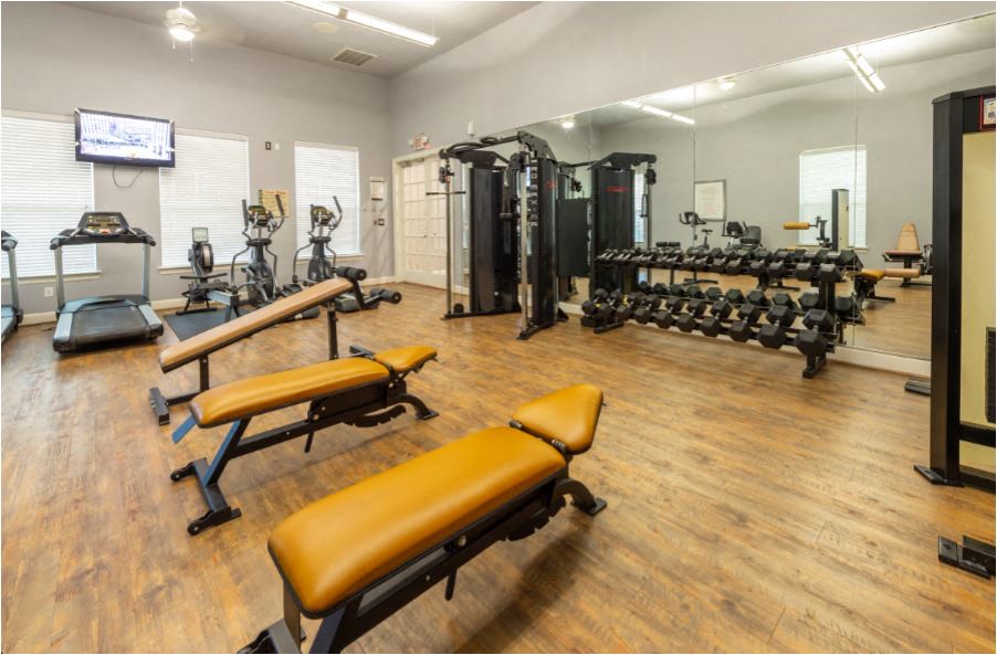 a fitness room with weights and cardio equipment and a tv