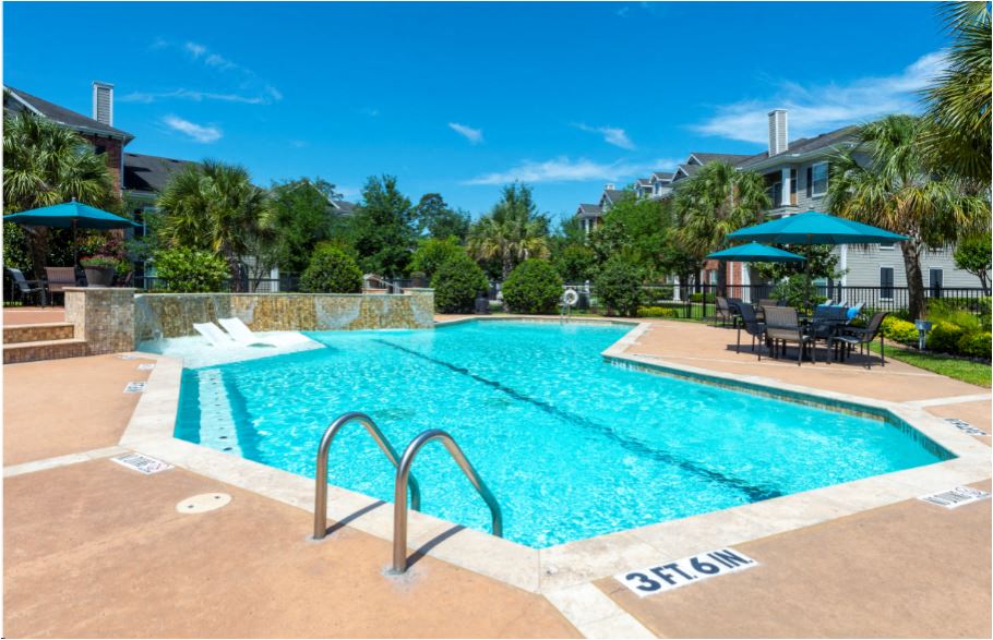 a swimming pool with chairs and umbrellas in front of a building