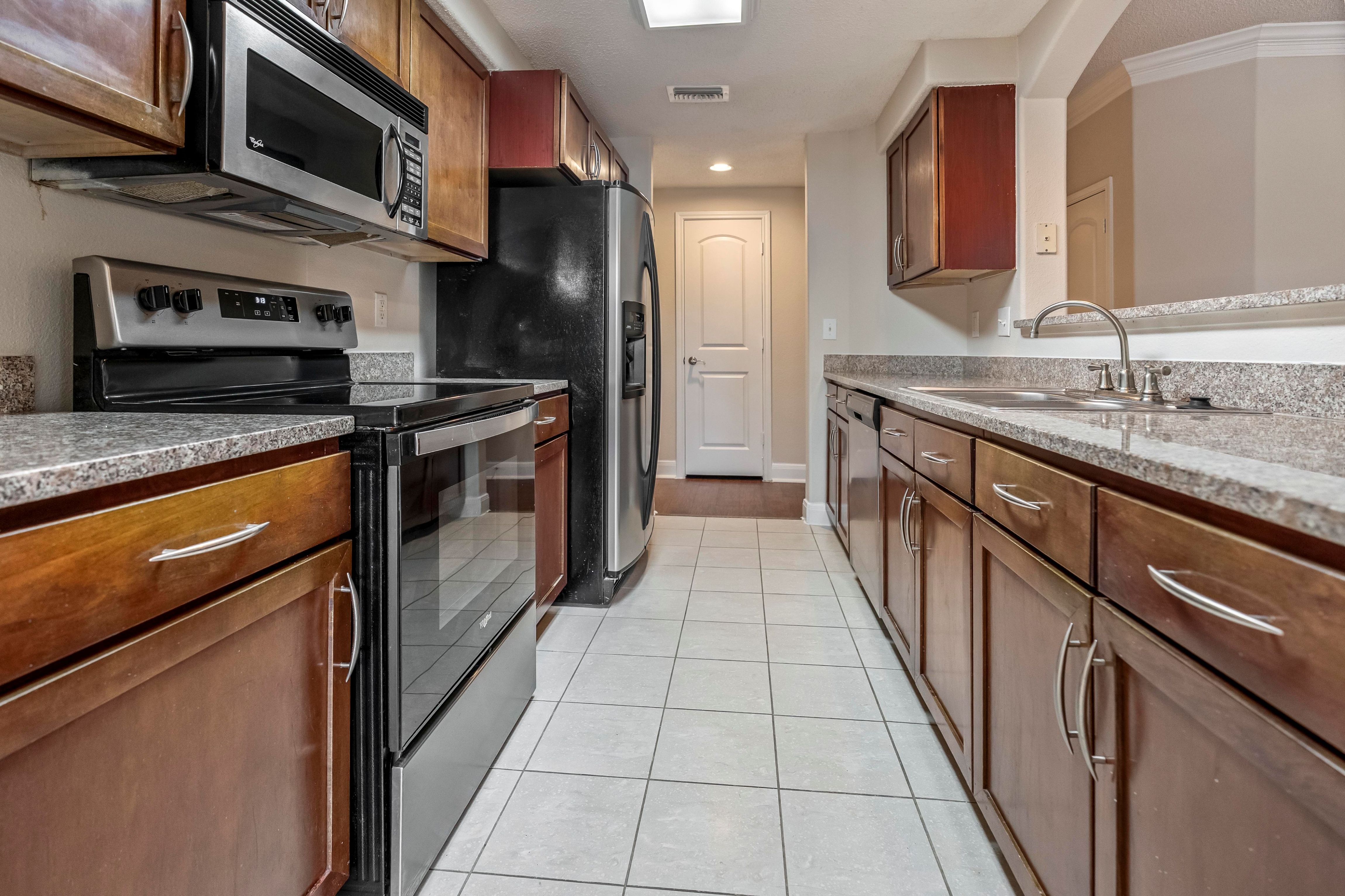 A kitchen with brown cabinets and black appliances.