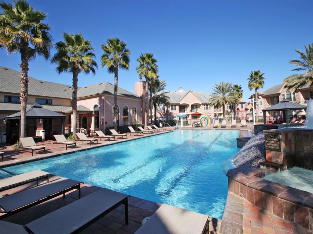 a large swimming pool with palm trees in front of a resort