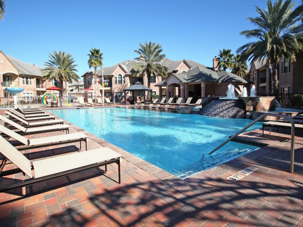 a large swimming pool with benches and palm trees