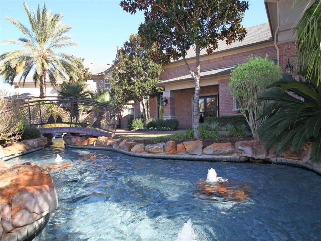 a pool with three ducks swimming in it in front of a house