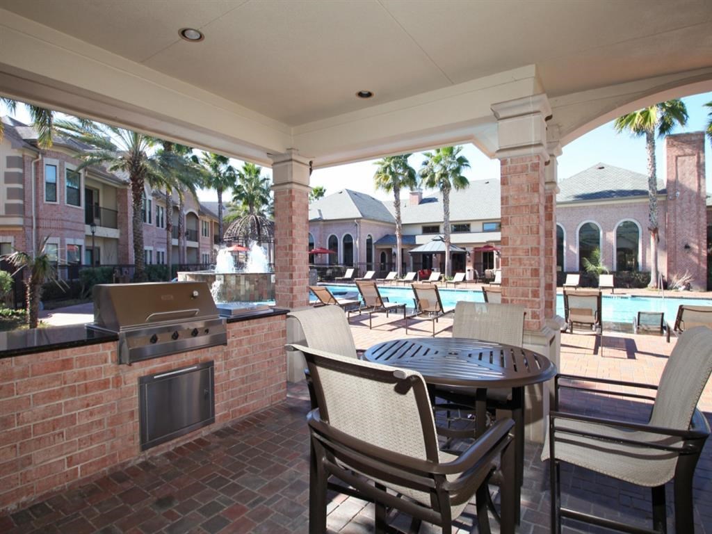 a covered patio with a grill and a table and chairs