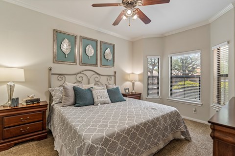 A bedroom with a large bed and a ceiling fan.