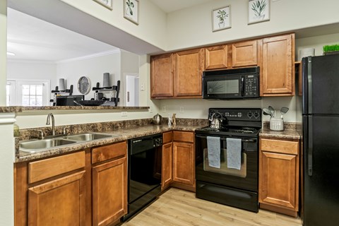 A kitchen with wooden cabinets and black appliances.