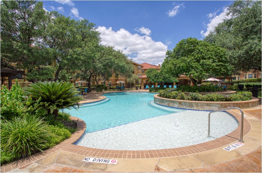 a large swimming pool with a fountain and trees