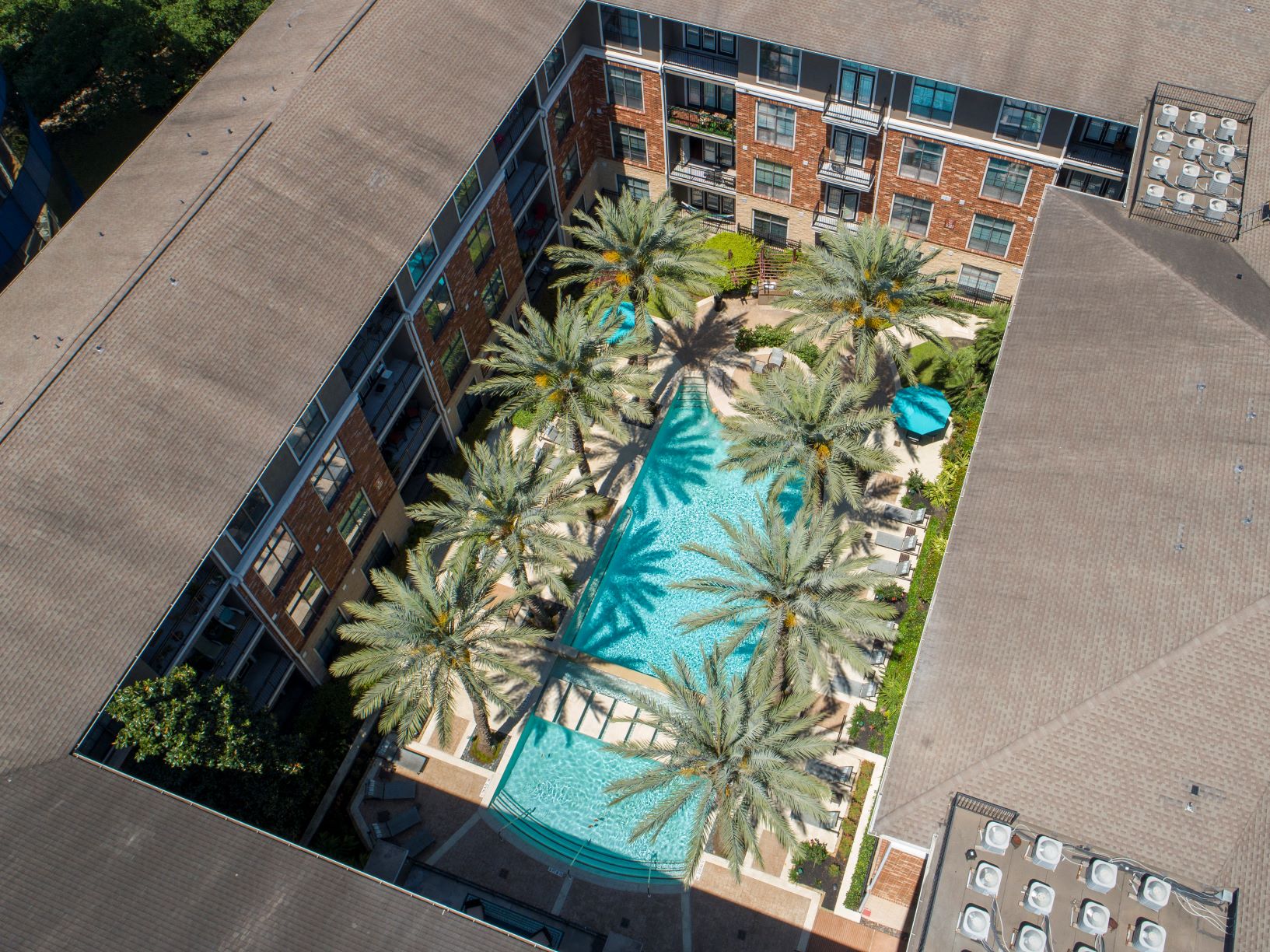 an overhead view of a building with a pool and palm trees