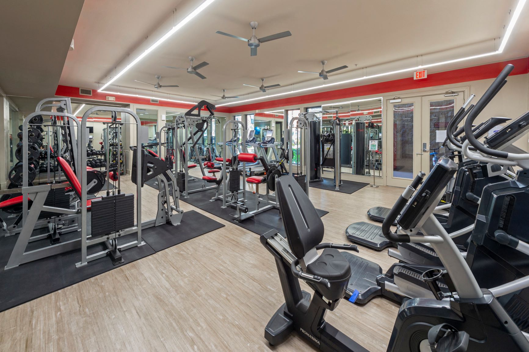 a gym with cardio equipment and weights on a wood floor