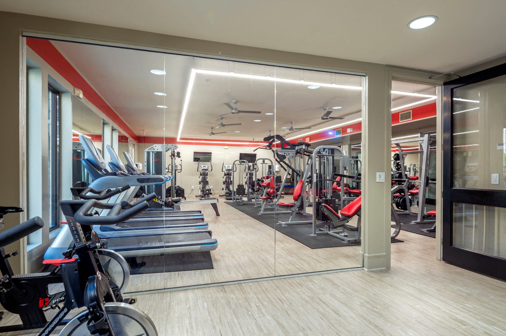 a gym with cardio equipment and mirrors in a building