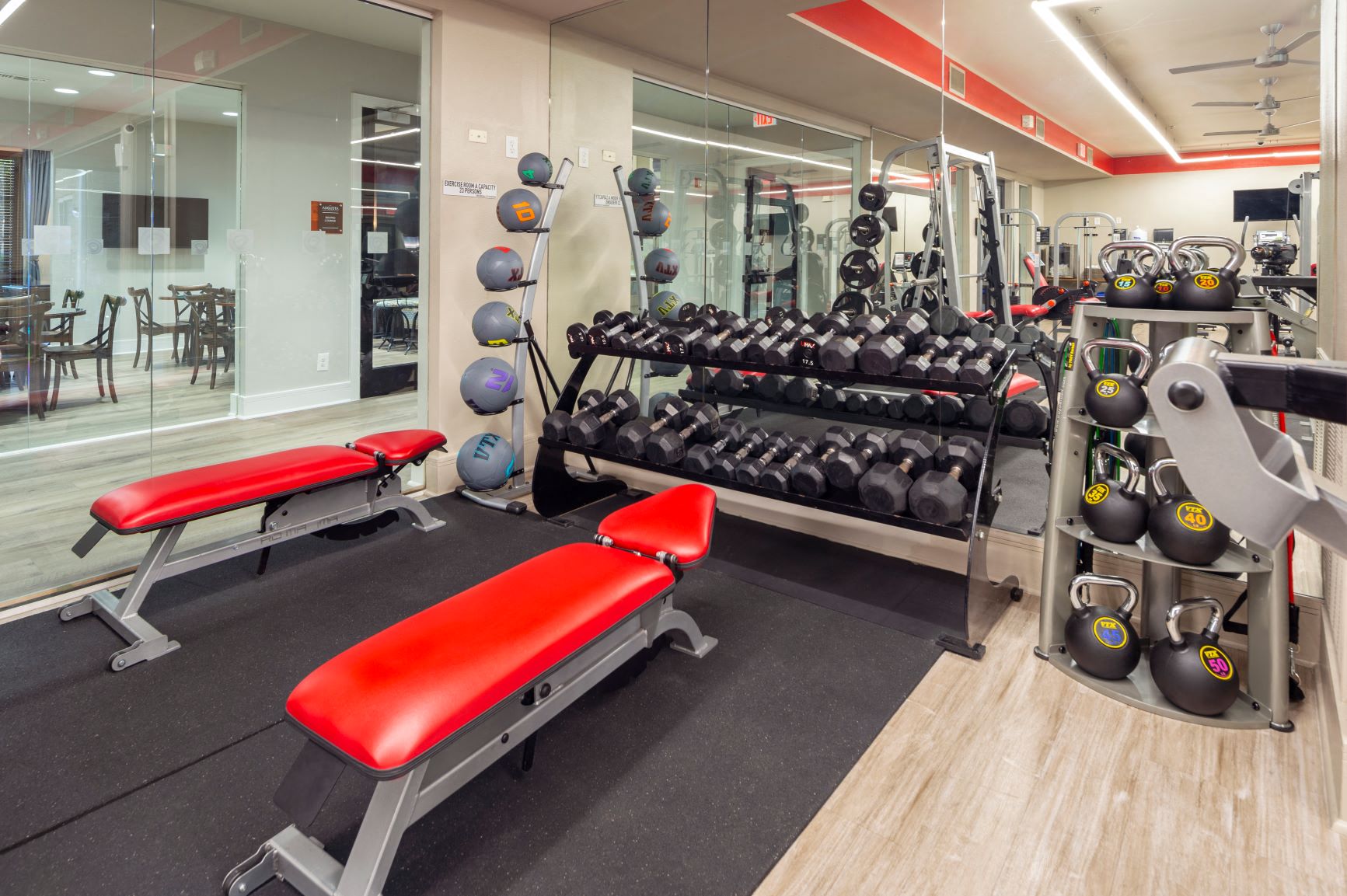 a gym with weights and a red bench