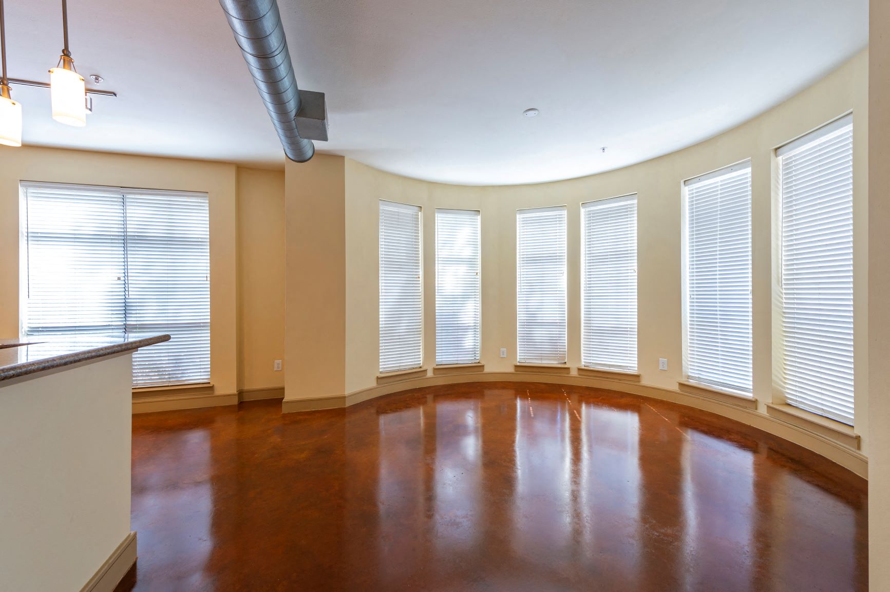 an empty living room with windows and a wood floor