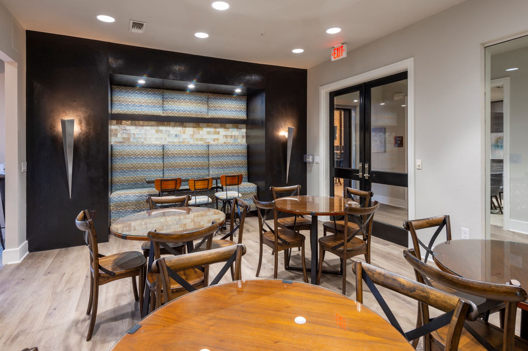 a dining room with wooden tables and chairs and a black wall with a large window