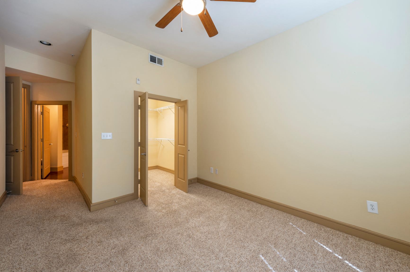 a bedroom with a ceiling fan and a door to a closet