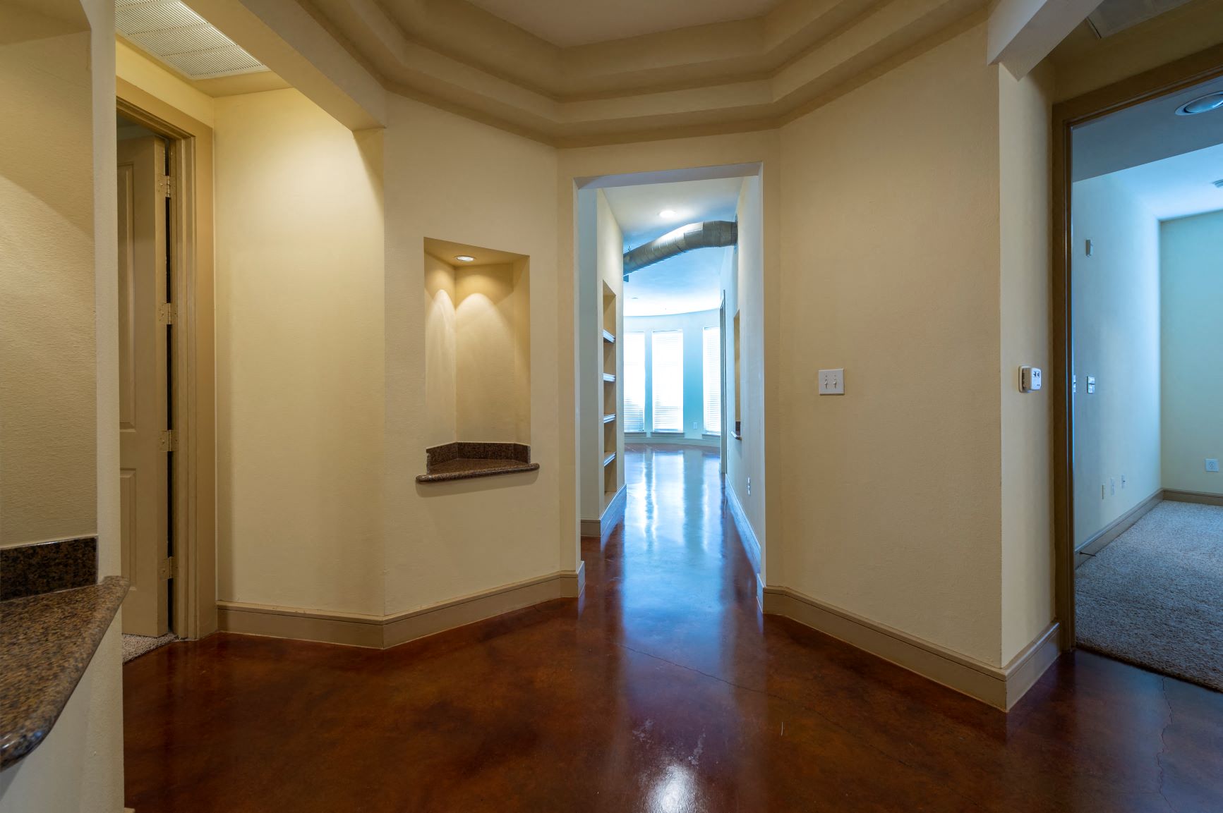the living room and hallway of a home with a wood floor and white walls
