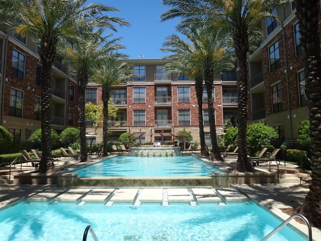 a large pool with palm trees in front of an apartment building