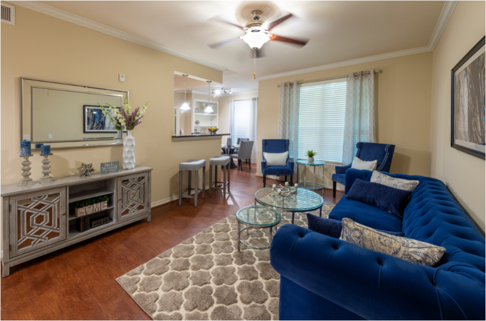 a living room with blue furniture and a ceiling fan