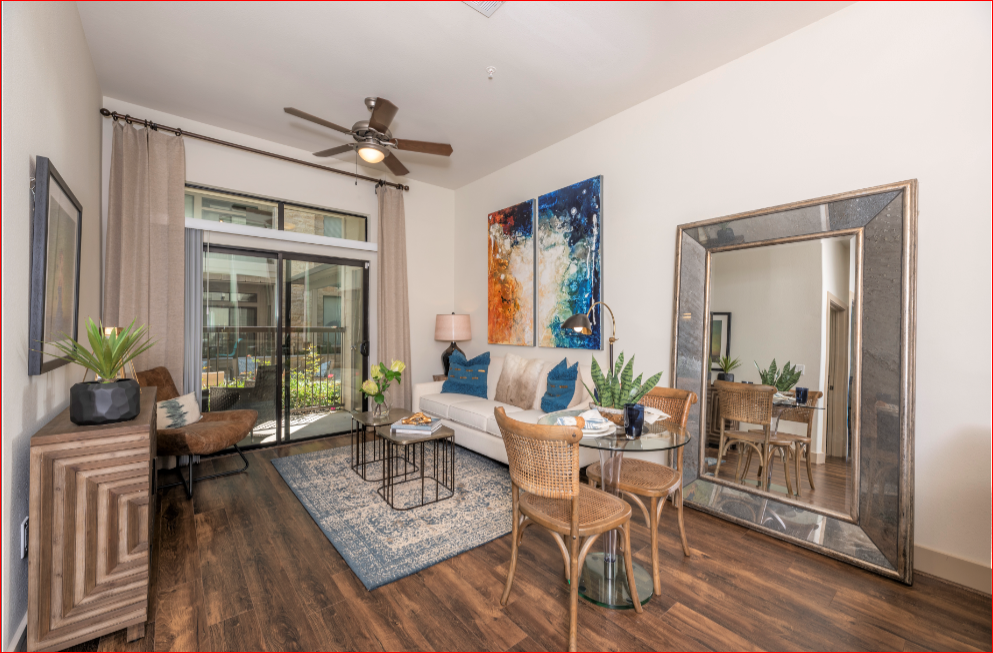 a living room with a couch and a ceiling fan and a large mirror