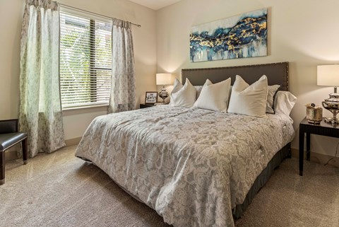 A bedroom with a large bed and a painting on the wall.