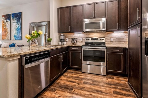 A modern kitchen with dark wood cabinets and stainless steel appliances.