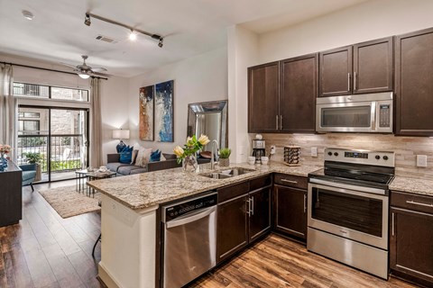 A modern kitchen with dark wood cabinets and stainless steel appliances.
