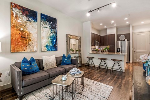 A living room with a grey couch and a painting on the wall.