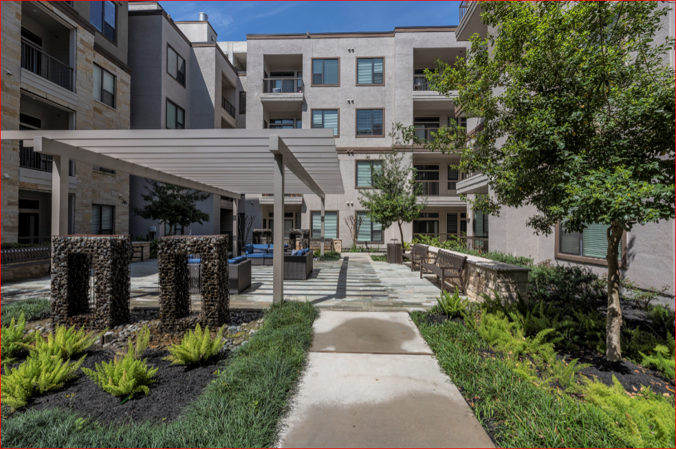 an outdoor courtyard with trees and a sidewalk in front of an apartment building
