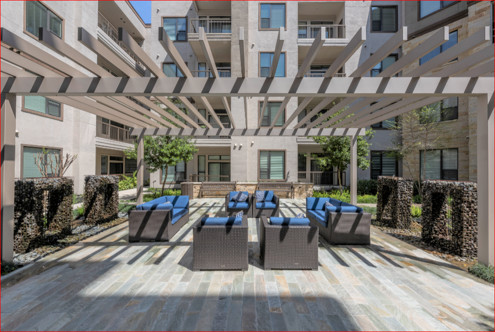 a lounge area with chairs and tables in front of an apartment building