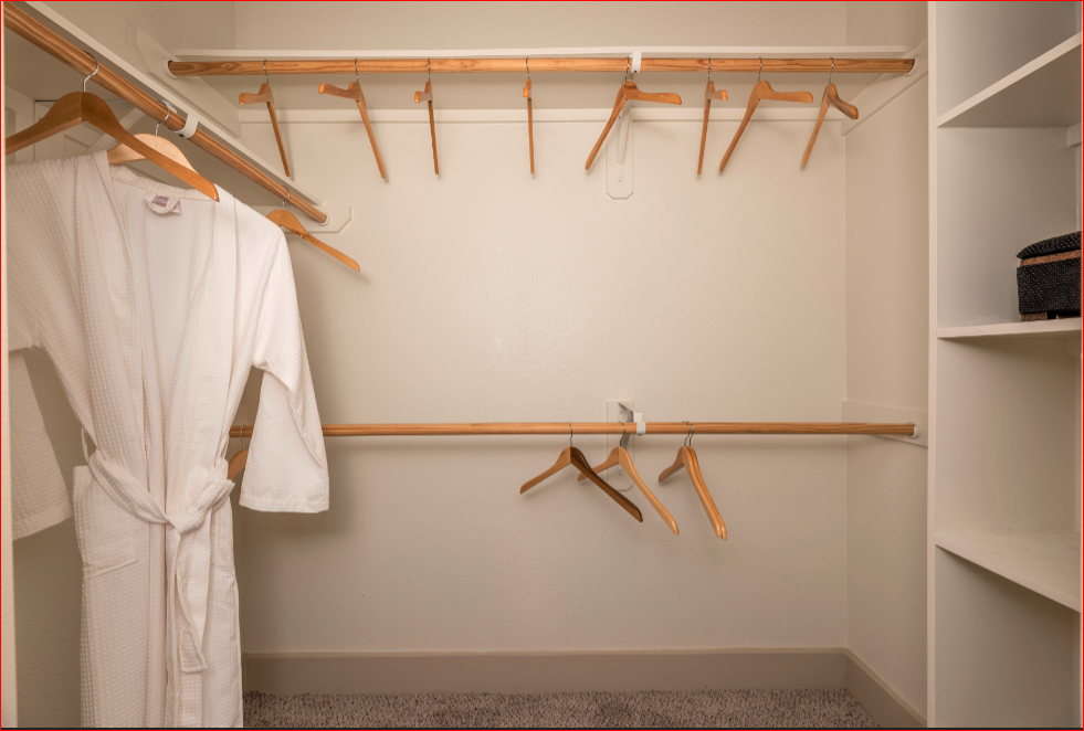 a walk in closet with a robe and hangers on the wall