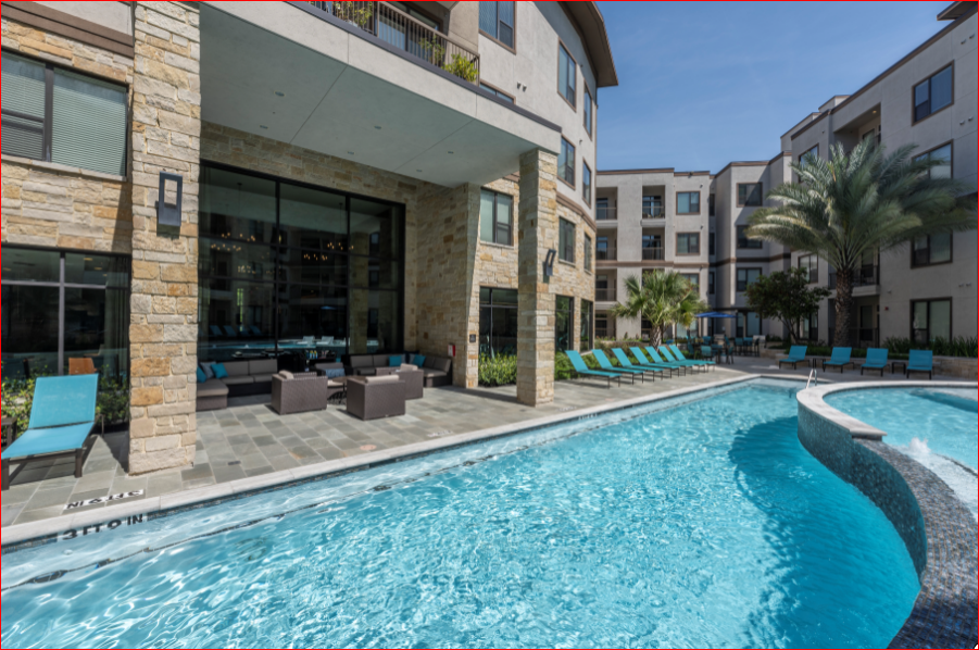 a swimming pool with blue lounge chairs and a building in the background