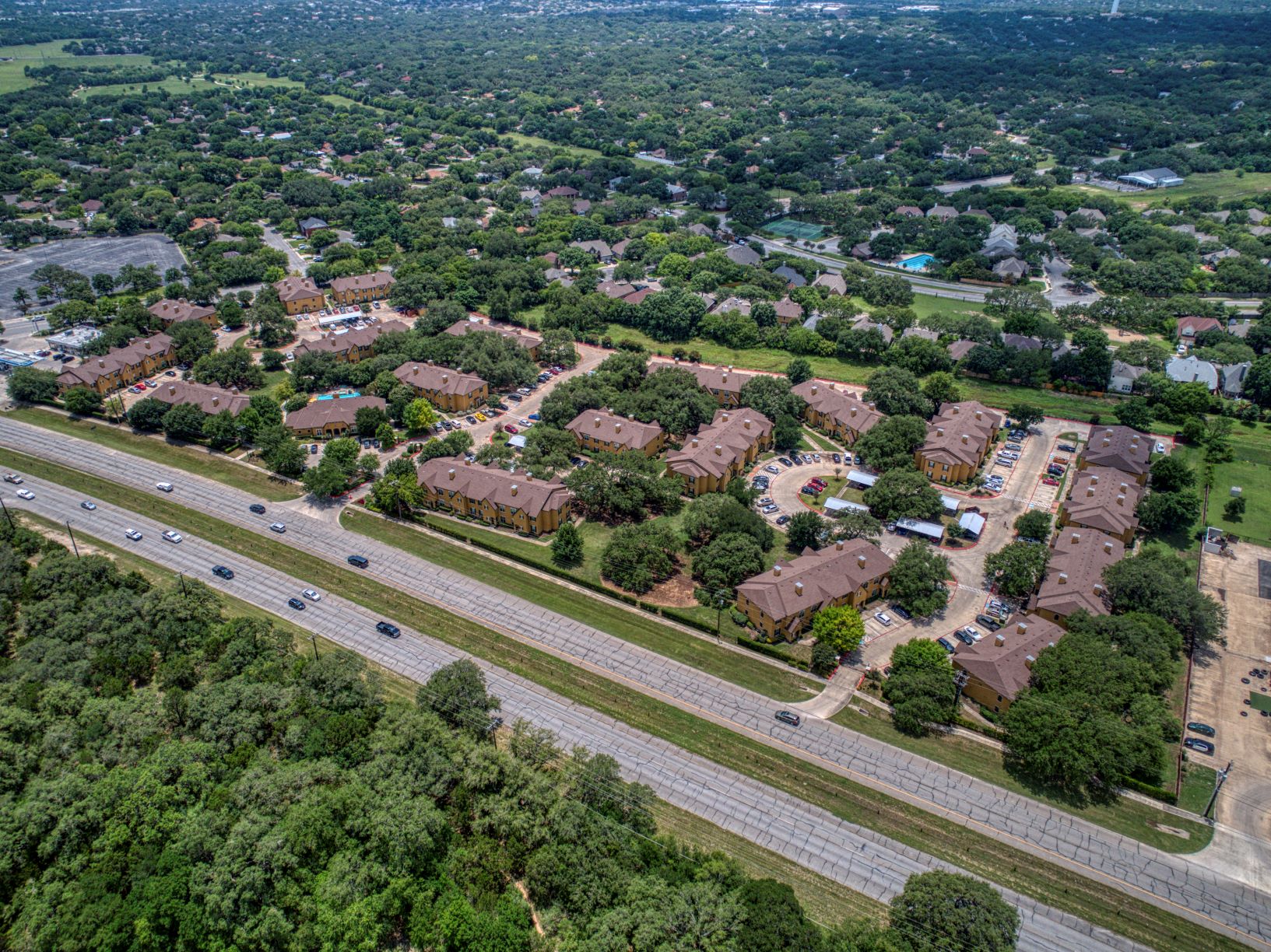 an aerial view of a suburban neighborhood with cars on a highway