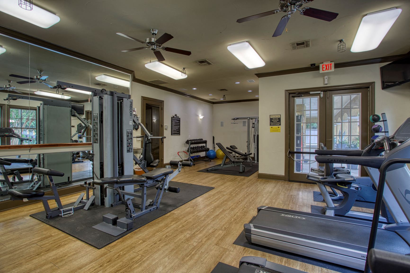 a gym with weights and cardio equipment and a glass door