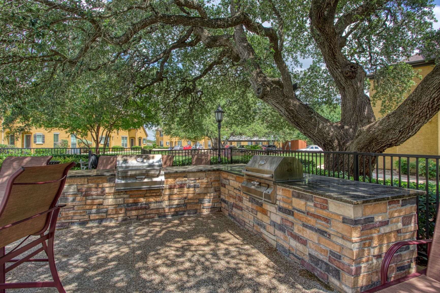 a brick patio with a grill and a tree
