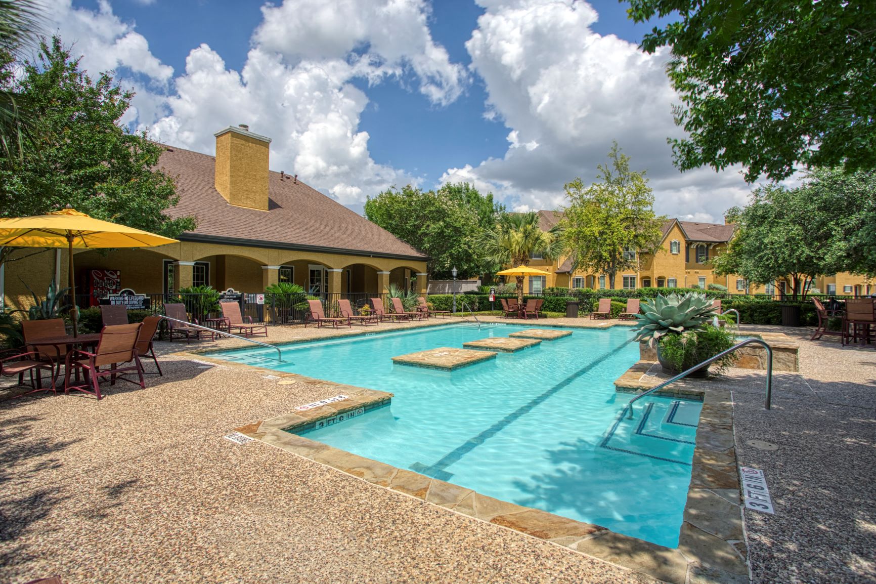 a large swimming pool with tables and chairs around it