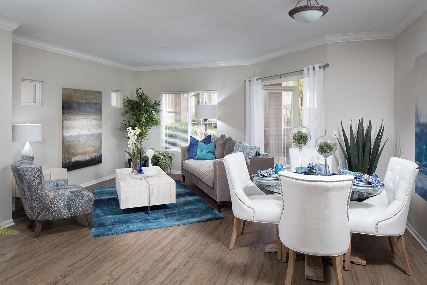 A living room with a blue rug and white chairs.