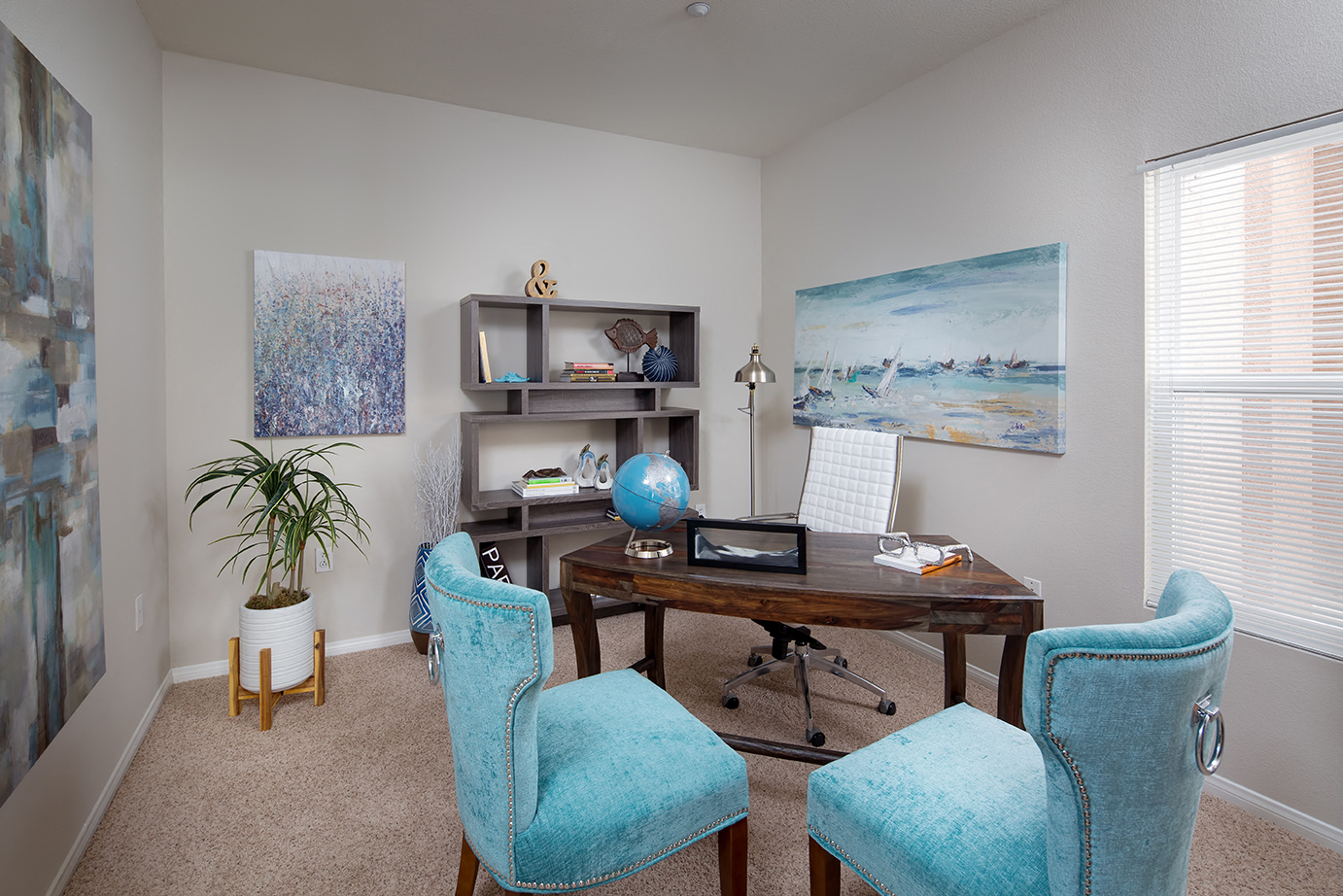 A room with a desk, chairs and a plant.