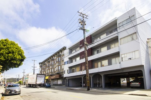 A street view of a residential area with cars and buildings.
